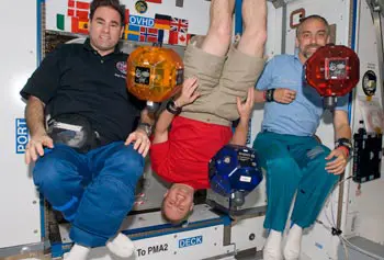 Three volleyball-size SPHERES robots float freely inside the International Space Station during a test in October 2008. Looking on from left are astronauts Greg Chamitoff and Michael Fincke and American space tourist Richard Garriott.