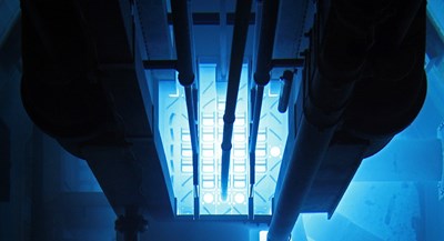 Nuclear reactor with pipes headed down into a blue lit interior area.