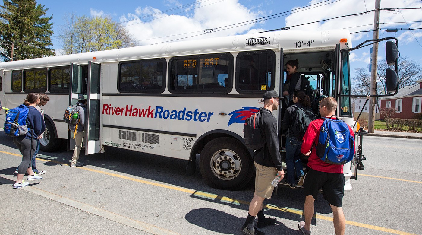Students getting on a UMass Lowell River Hawk Roadster bus.