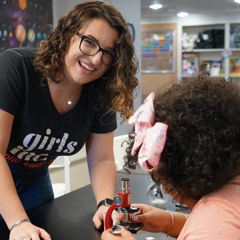 Education major Sydney Fugundes works with student who is using a microscope