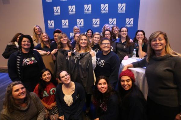 Boston Marathon bombing survivor Roseann Sdoia, center in white jacket, poses with current and former members of Alpha Omega, the UMass Lowell sorority she was in, after speaking at University Crossing Thursday.