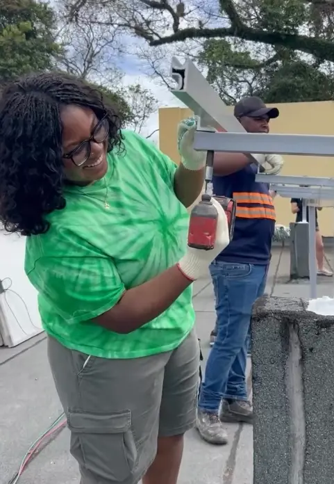 Nadia Eshun uses a drill to install a solar panel mount.
