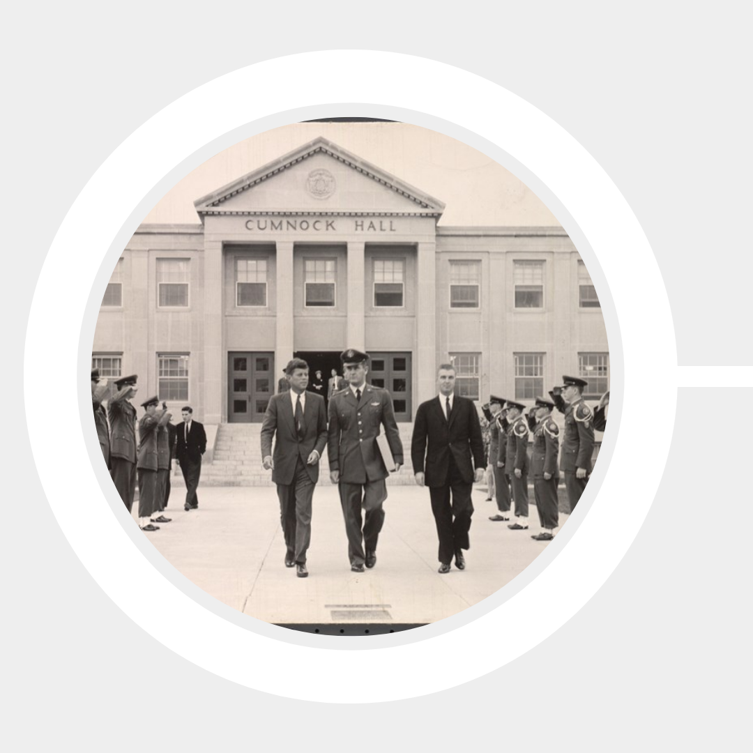 John F. Kennedy exits Cumnock Hall through an aisle of regimented soldiers in formation.