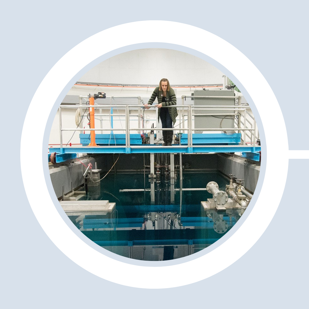 Student standing on a platform above the open-pool nuclear reactor looks down to examine the well.