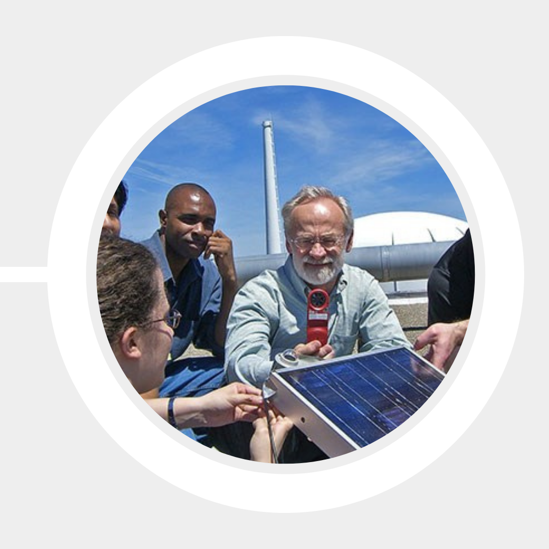 Prof. John Duffy demonstrates a solar photovoltaic panel to students outside Pinanski Hall.