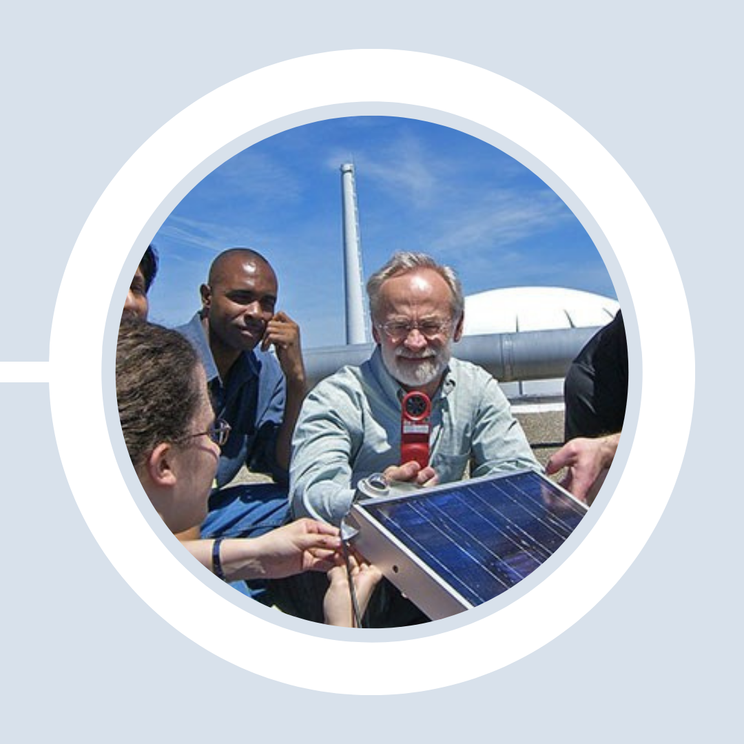 Prof. John Duffy demonstrates a solar photovoltaic panel to students outside Pinanski Hall.