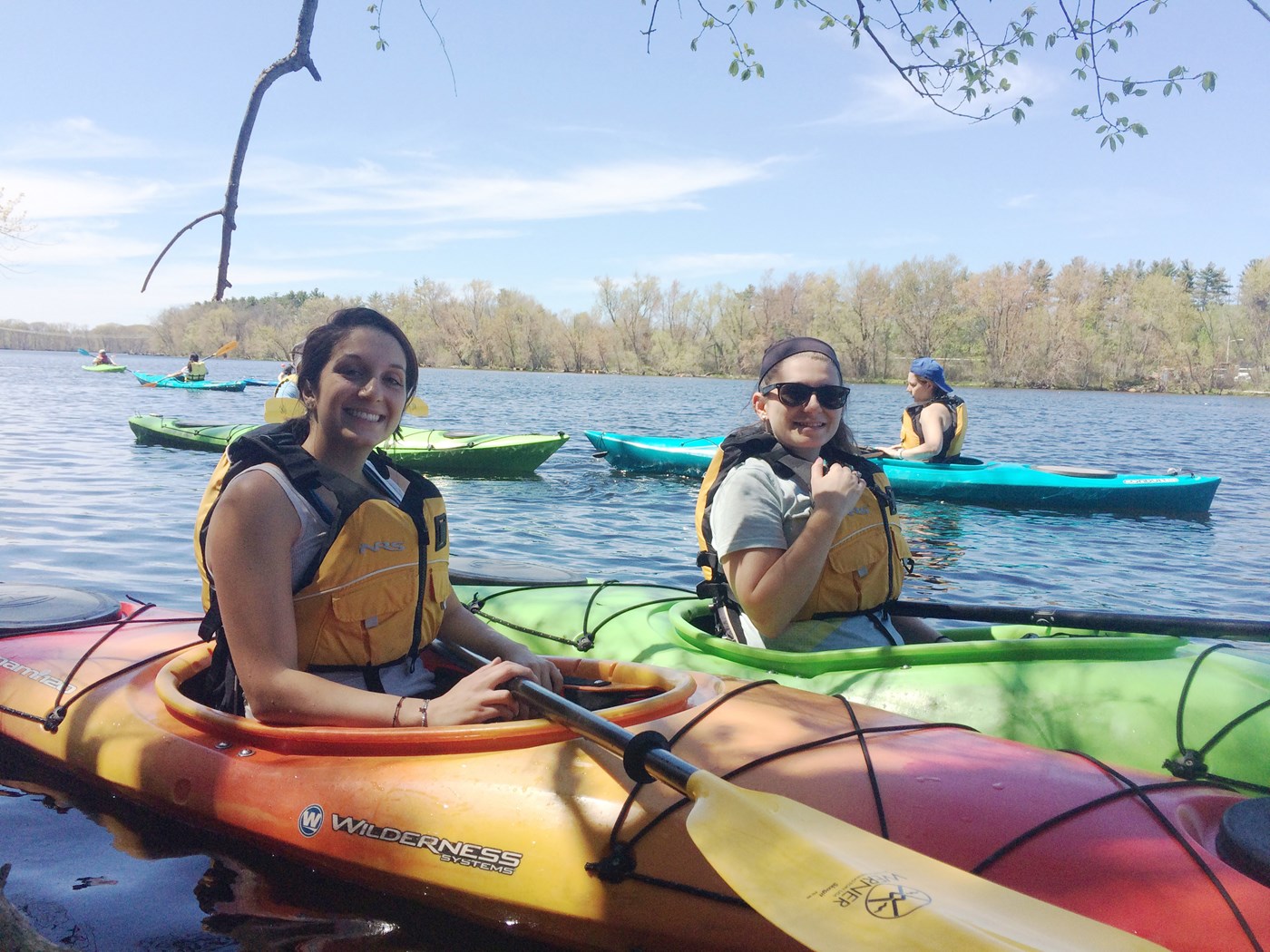 Students pose for picture smiling while kayaking.