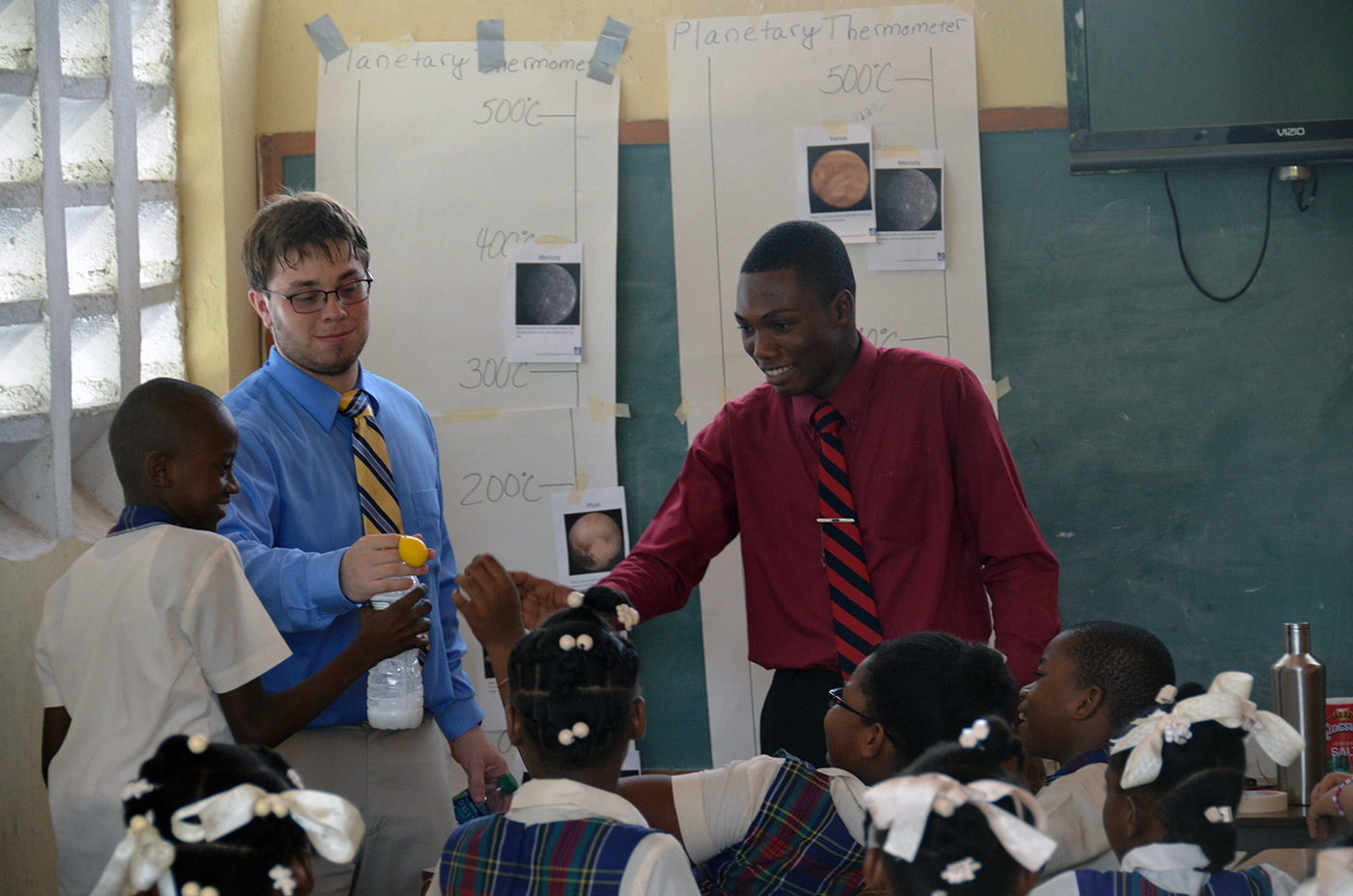 Two UMass Lowell male students doing a science demonstration for a classroom full of young Haitian children on a visit to Haiti in 2016.