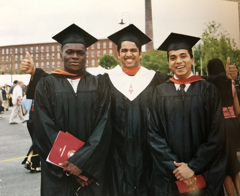 Three male students wear caps and gowns smiling at Commencement in 2000
