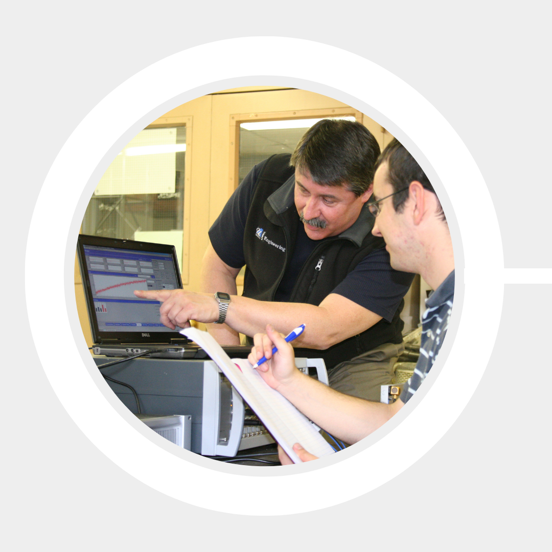 Prof. Peter Avitabile explains a software demonstration to a student at a computer.