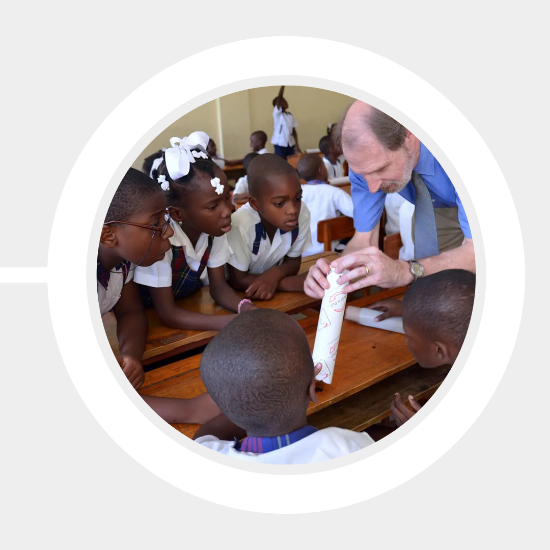 Prof. Robert Giles gives a demonstration to a group of Haitian students around a table.