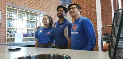 Campus Recreation student staff posing at welcome desk inside recreation center.