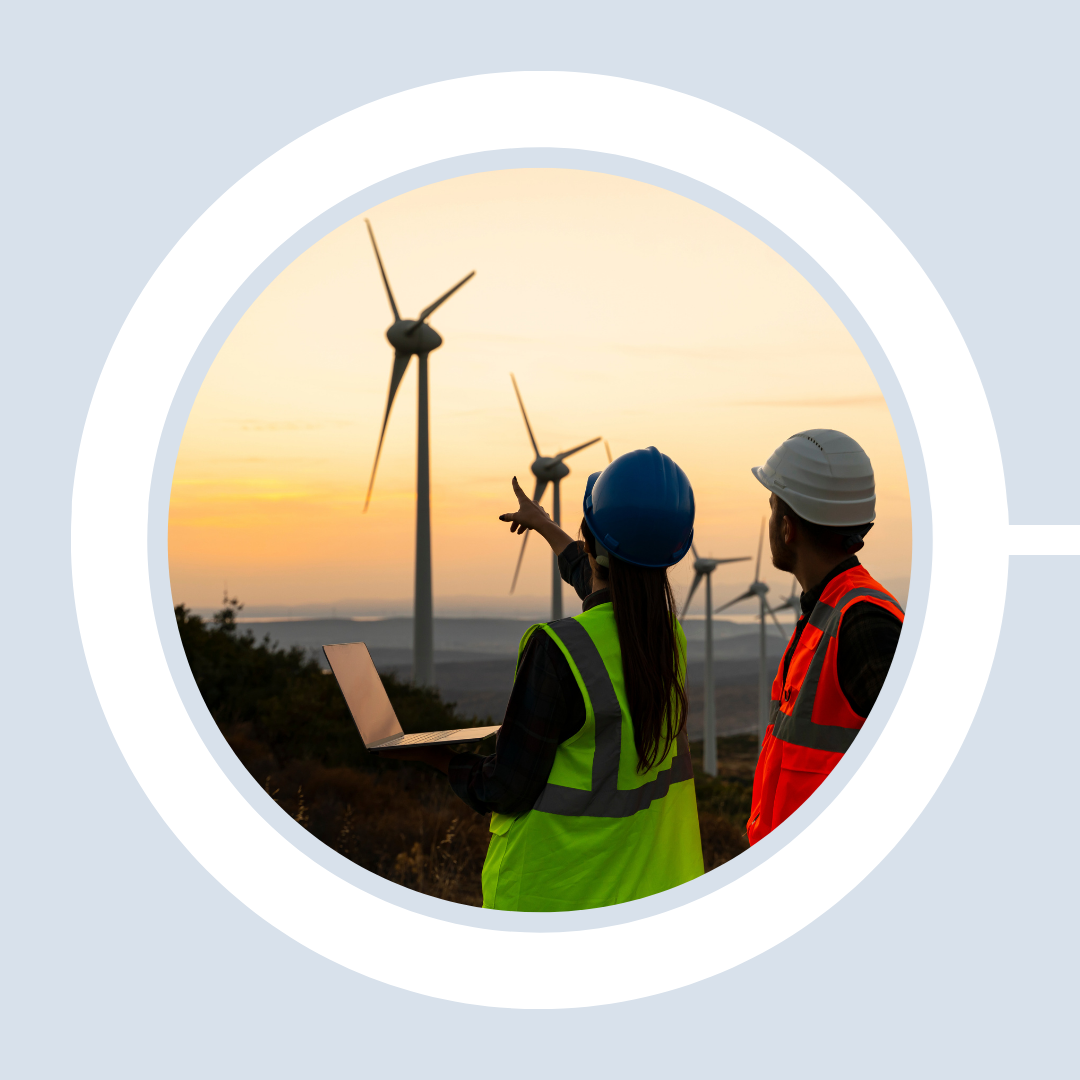 Wind energy technicians in the foreground monitor a wind farm and turbines from their computer.