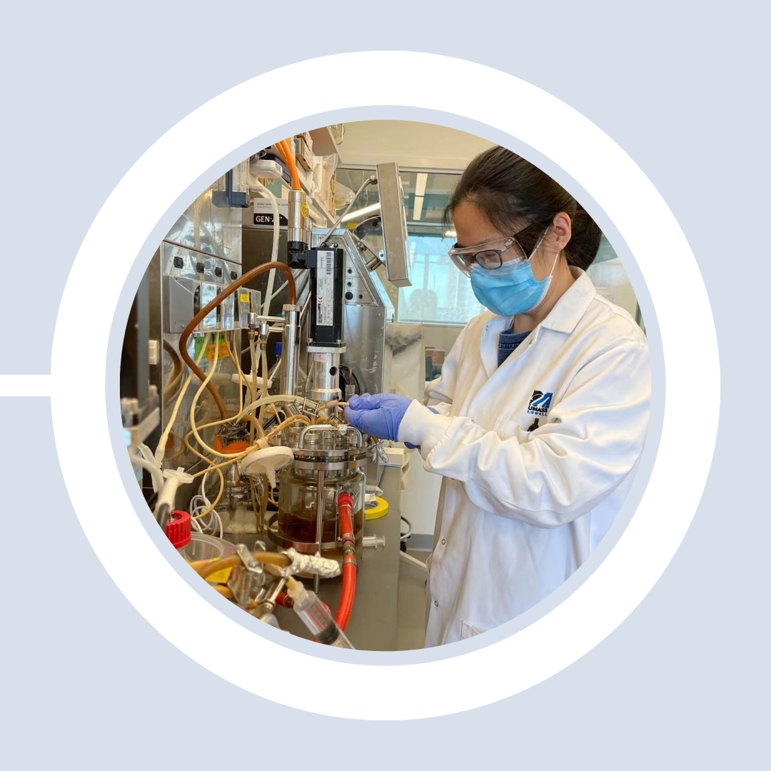 A student wearing protective gear experiments in the lab, connecting hoses to a container of liquid.