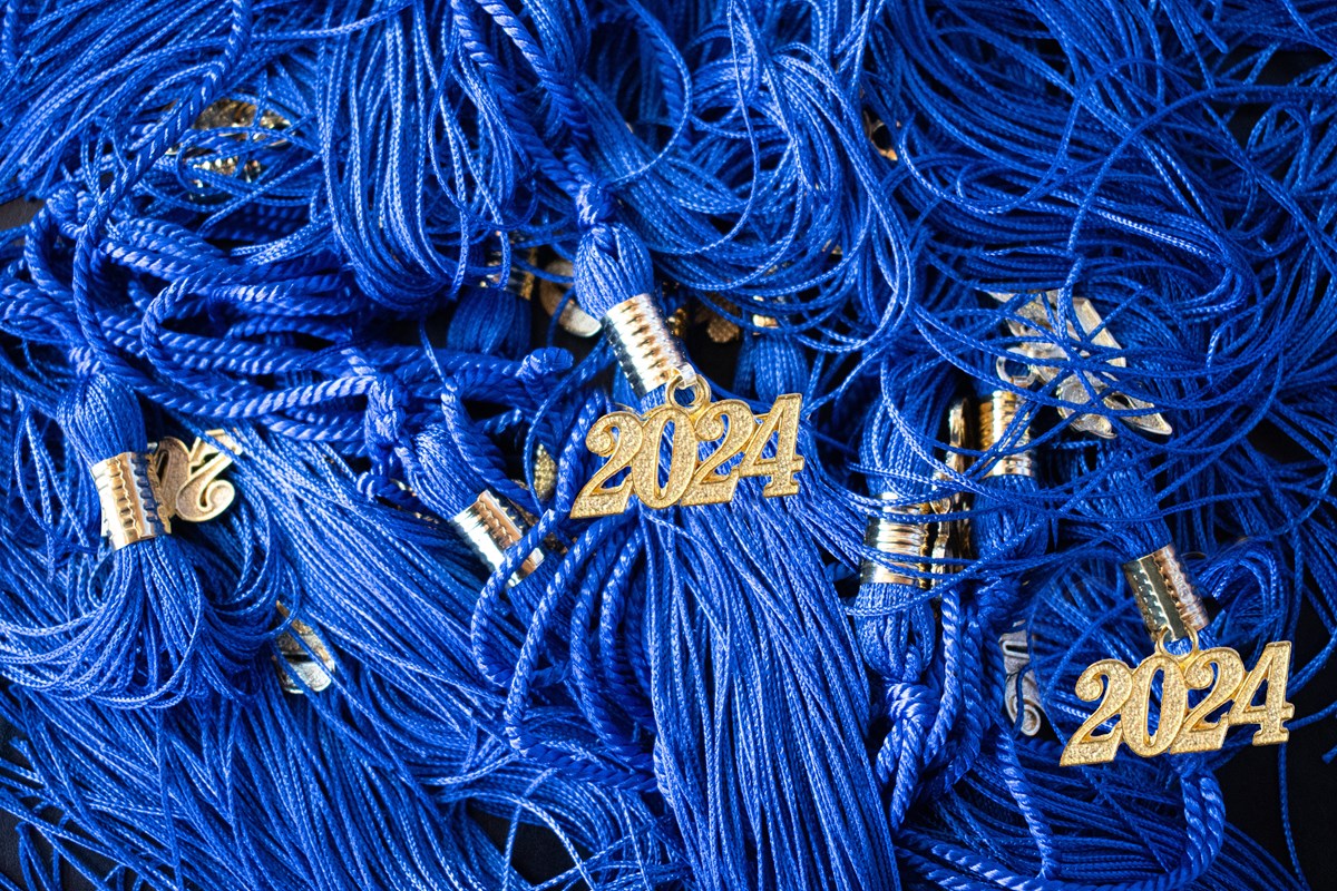 Pile of blue graduation tassels with golden 2024 on them