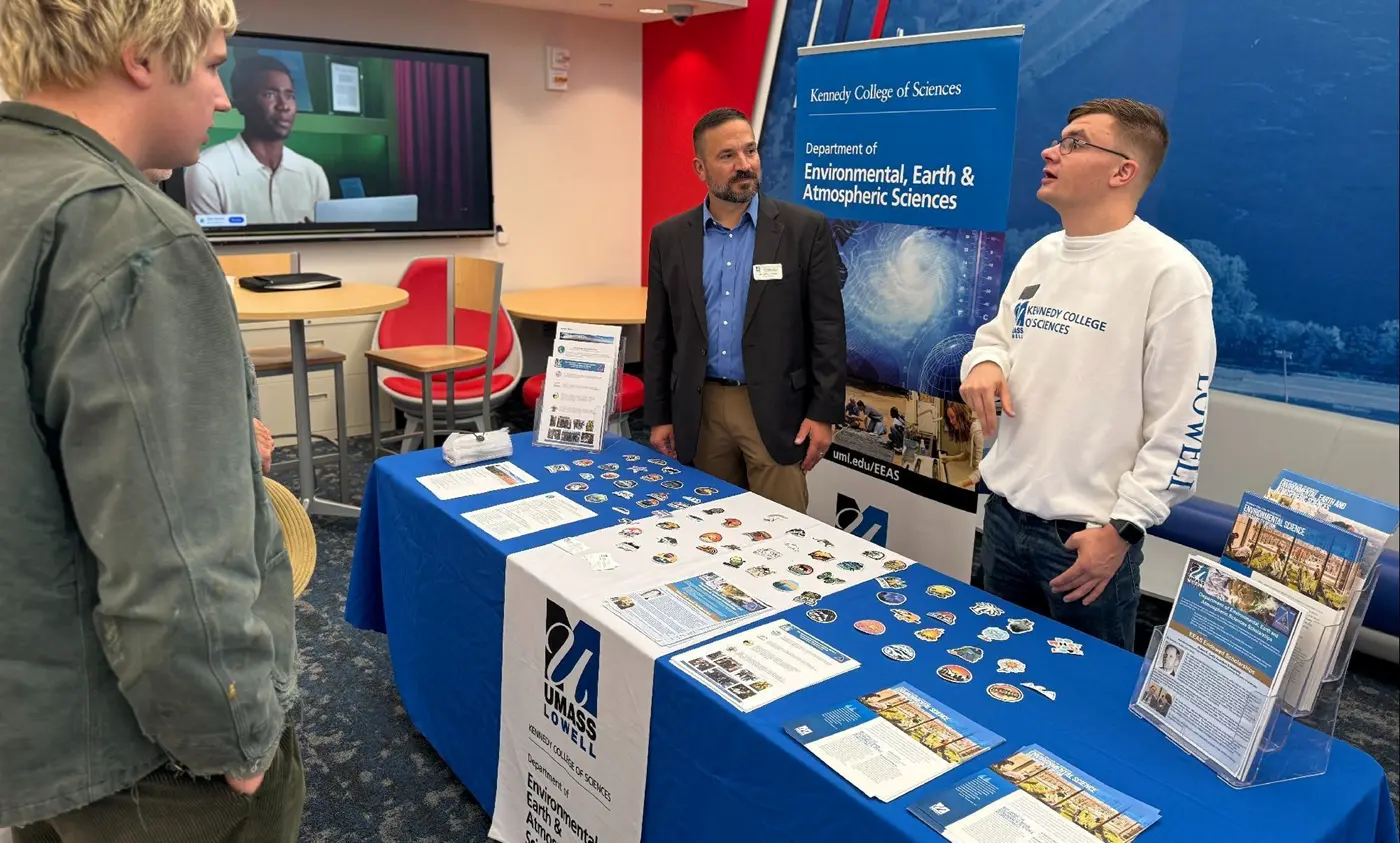 Two men stand behind a table in front of a Kennedy College of Sciences Department of Environmental Earth and Atmospheric Sciences banner