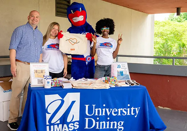 Image shows UMass Lowell dining hall staff wiith mascot Rowdy the River Hawk.