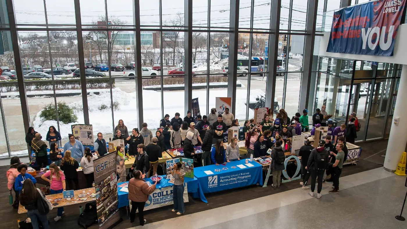 students around tables at an engagement fair in front of windows at University Crossing atrium