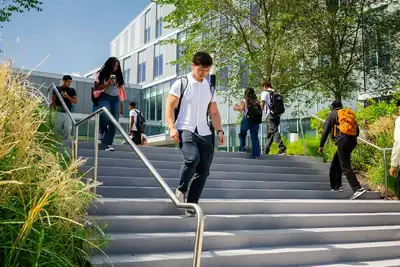 A student walks down the stairs outside the Pulichino Tong Business Center at UMass Lowell