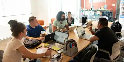 Group of student at table with laptops in Pulichino Tong Building