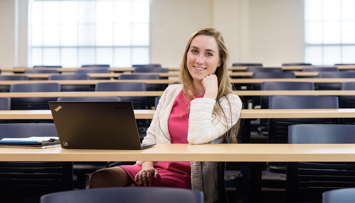 Graduate student Bridget McSherry smiles in classroom with her laptop