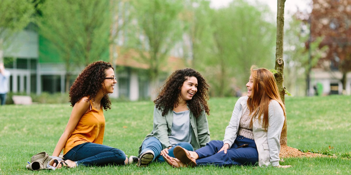 Three female students sit on the south lawn
