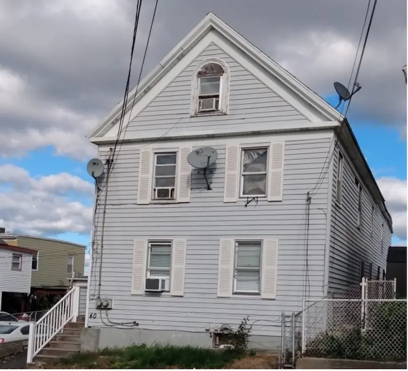 Exterior of three-story home with gable roof in Greek Revival style.