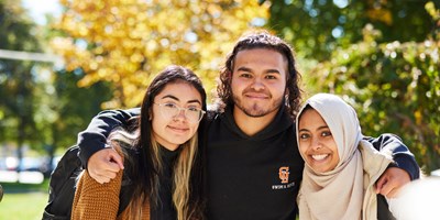 three students with arm around each other