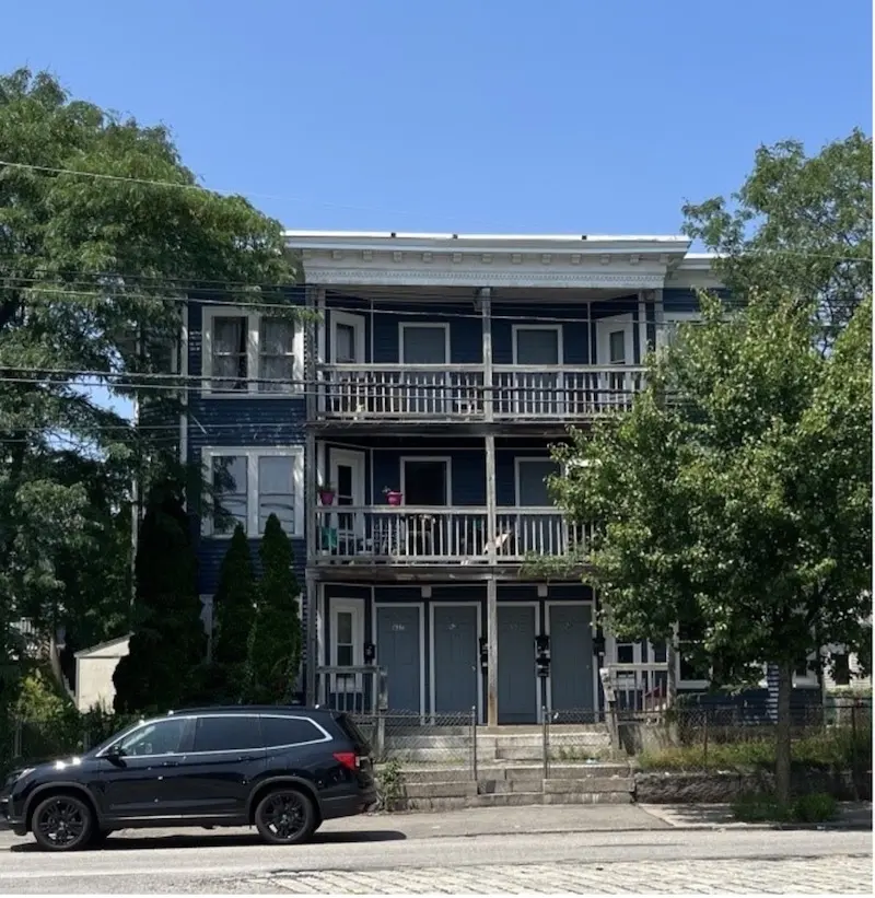 Exterior of triple decker with four doors and Italianate elements.