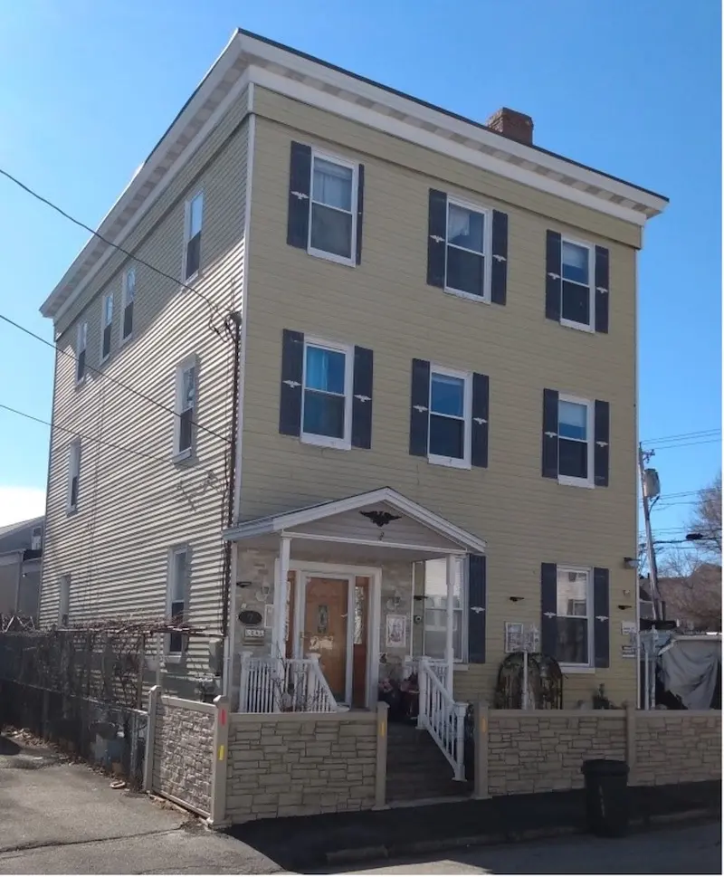 Exterior of three story home with Italianate features and flat roof.