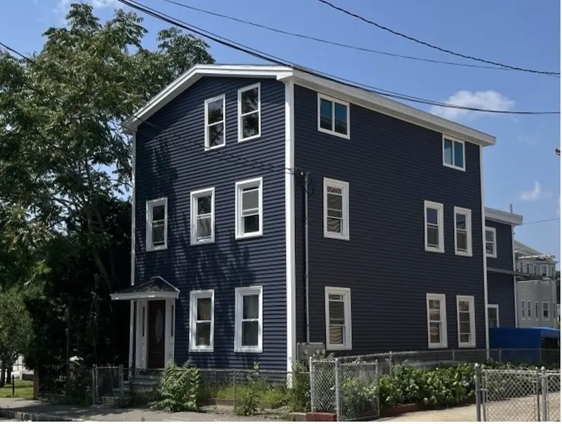 Exterior of side entrance of three story home in Greek Revival style.