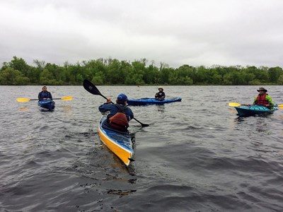 Three people in kayaks watching kayaking instructor