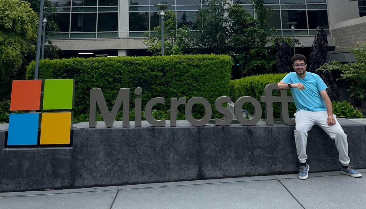 UMAss Lowell computer science student Abdullah Abou Mahmoud sits outside of an office building next to the Microsoft logo