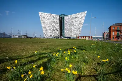 The exterior of the Titanic Museum in Titanic Quarter with beautiful yellow tiny flowers view in its front.