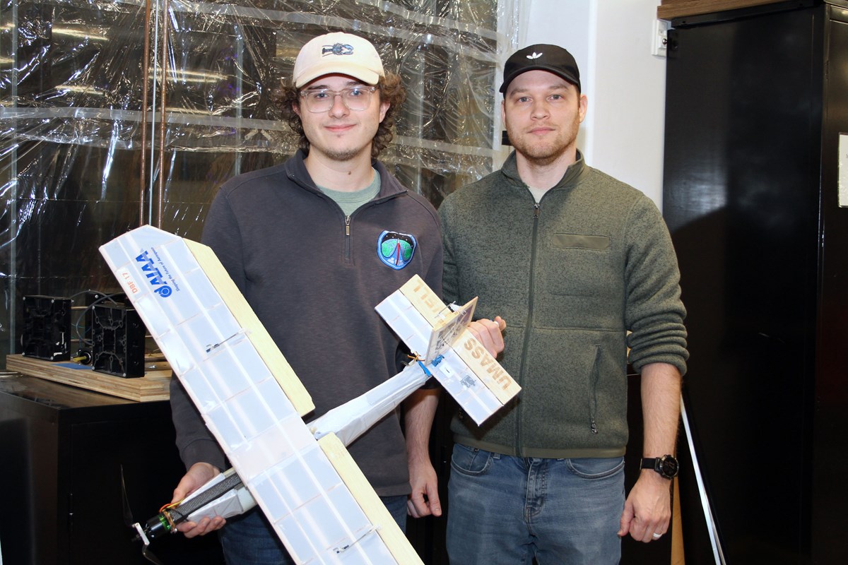 Mechanical engineering students Aiden Skidmore and Miklos Haranghy holding a model plane in a club room.