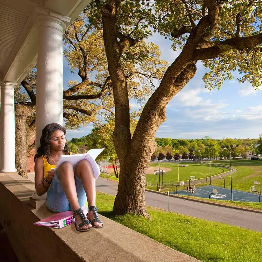 Student reading book on UMass Lowell campus.