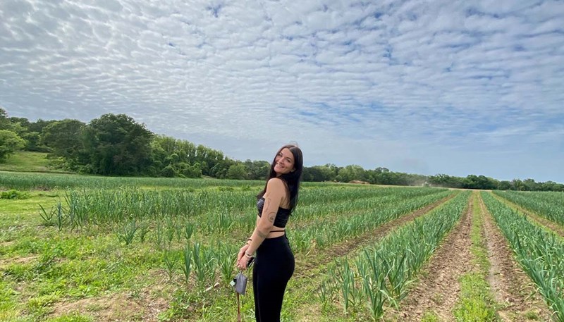 Alyssa Puglisi stands on an agricultural field with a blue sky above her
