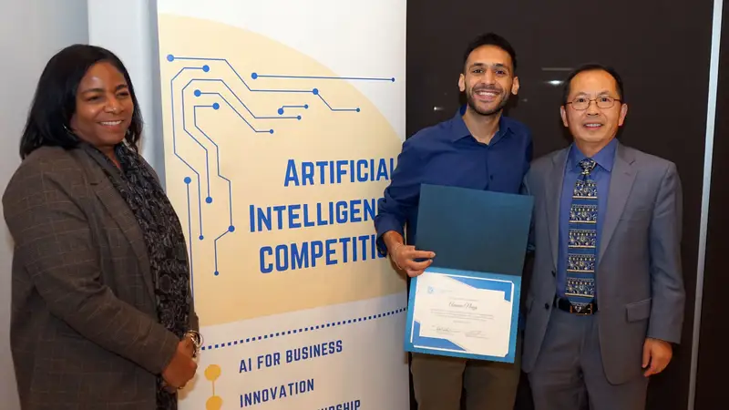 Ammar Nagy standing with two people in front of a sign, "Artificial Intelligence Competition, AI for business innovation."