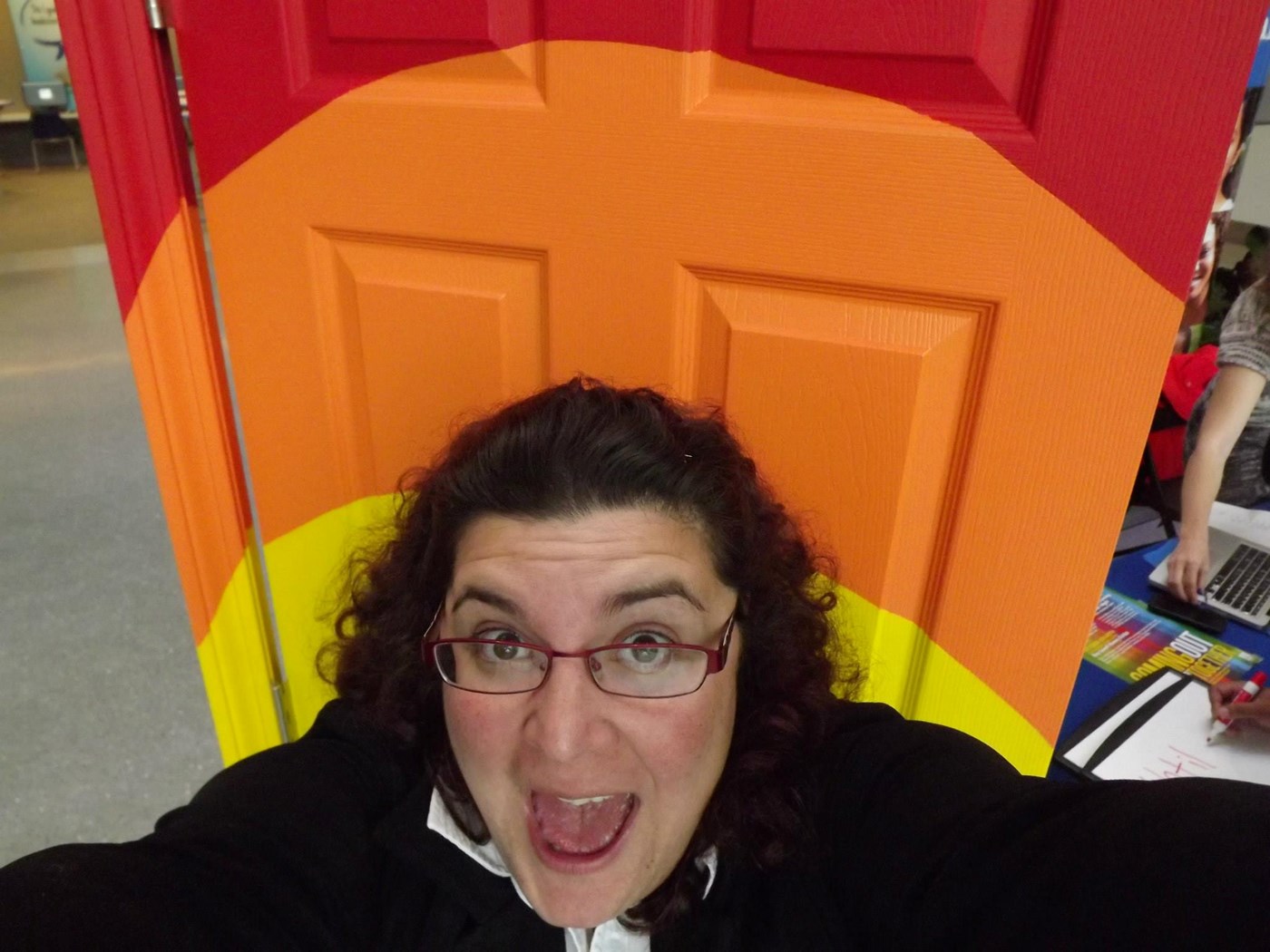 Person taking a selfie in front of a rainbow-colored door