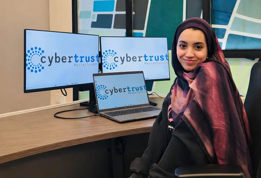 Asmaa Amiar sits in front of CyberTrust computers.