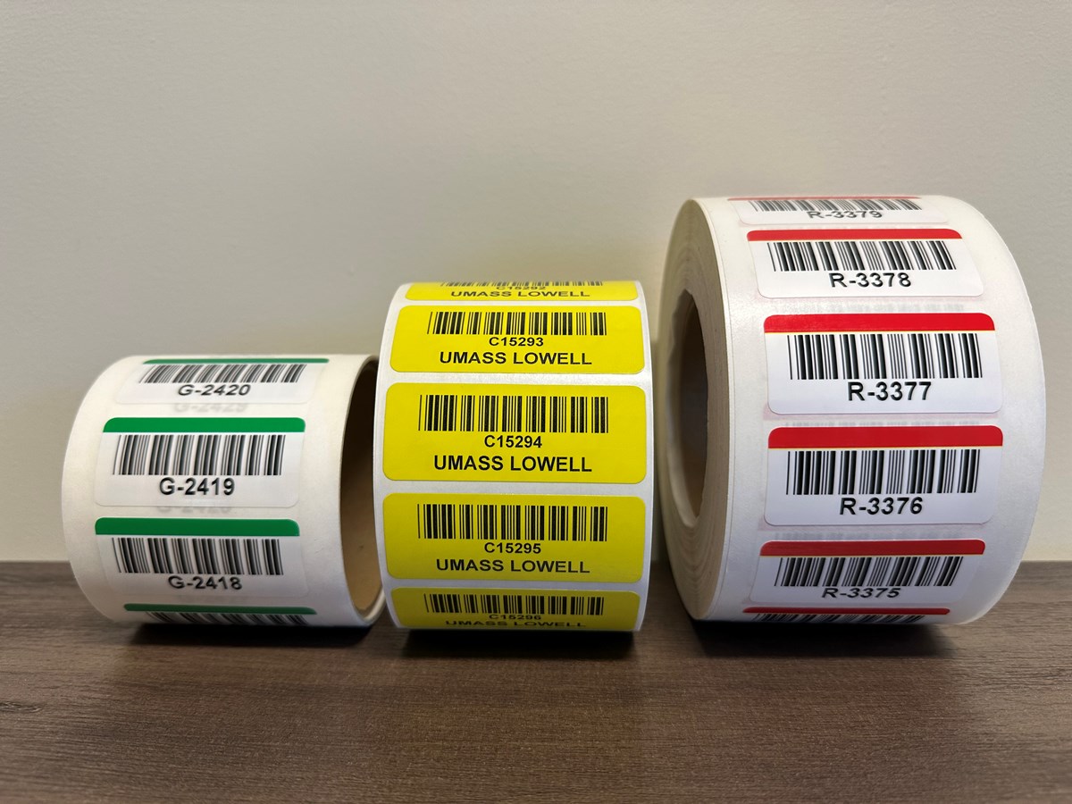 3 rolls of asset tags: green, yellow and red. They have barcode serial numbers; the yellow one also has the words UMass Lowell.