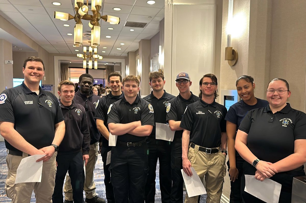 10 people in EMS uniforms pose for a group photo in a hotel hallway.
