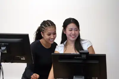 Two students look at a computer screen.