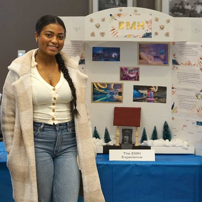UMass Lowell business student poses in front of an educational display