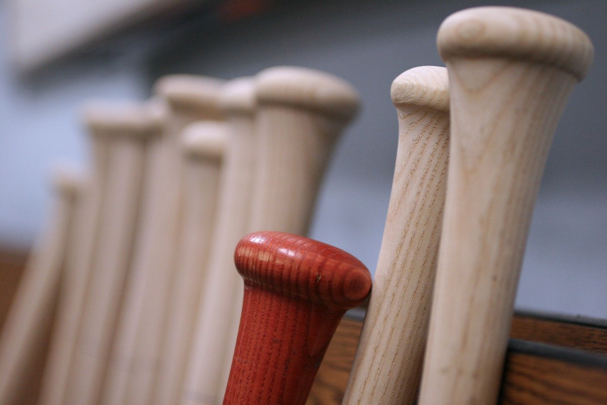 Baseball bats lined up against a wall. 