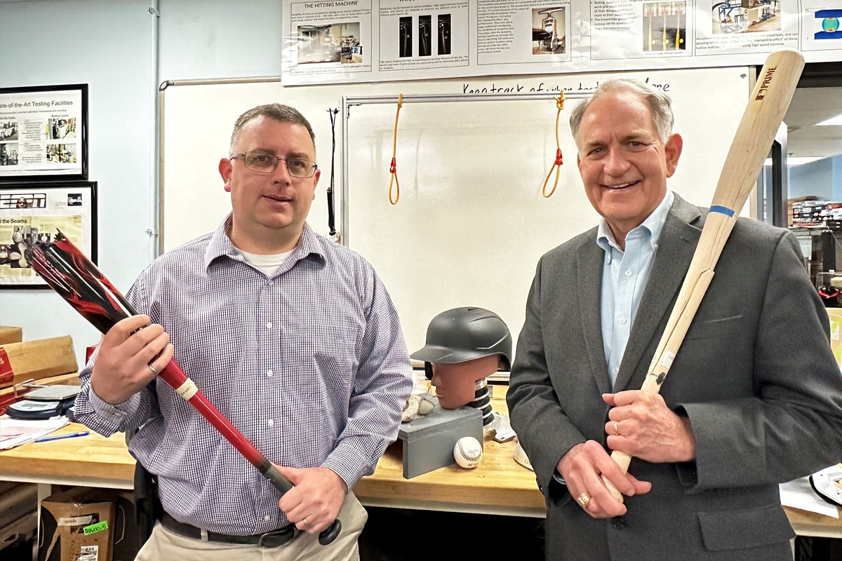 Patrick Drane and James Sherwood holding baseball bats inside the UMass Lowell Baseball Research Center.