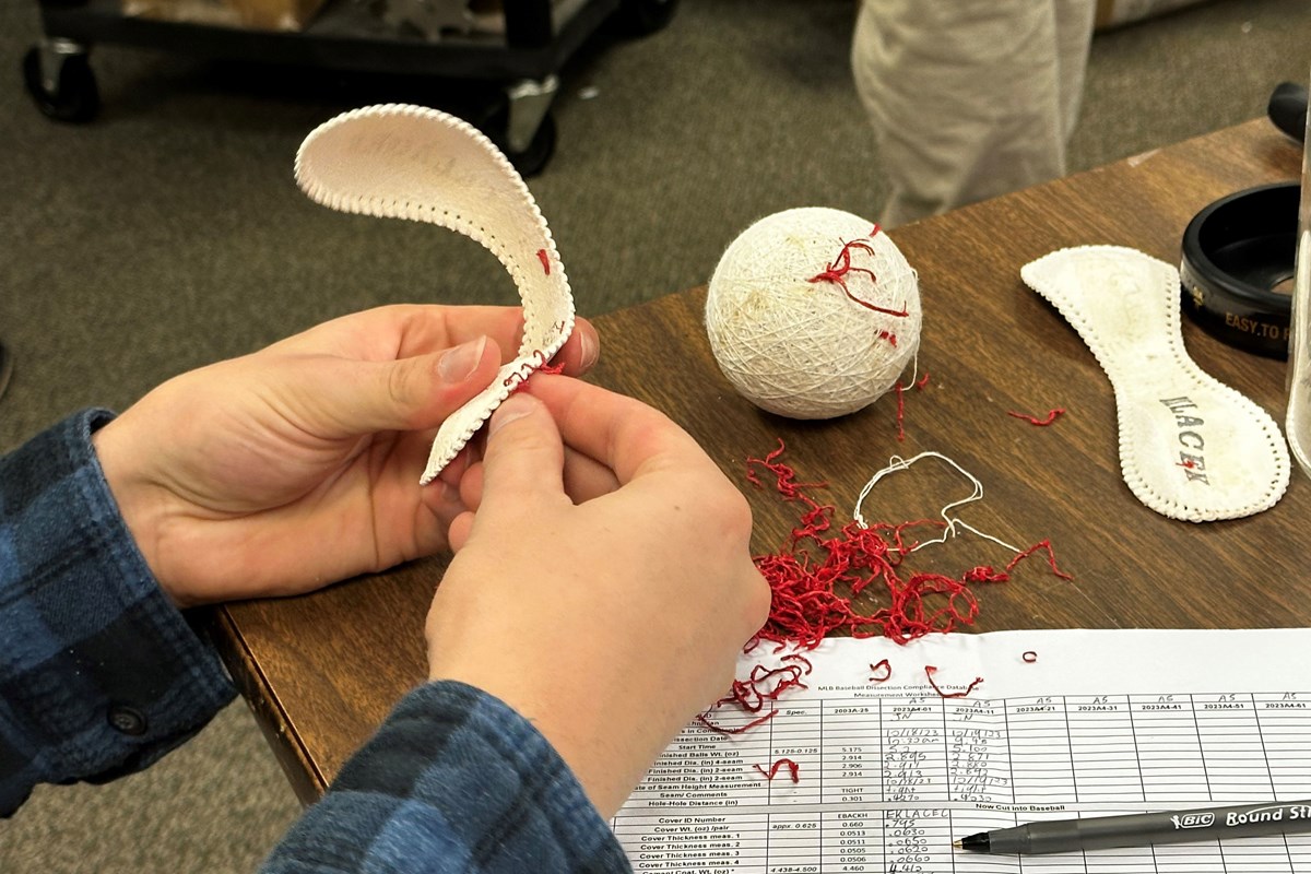 A student dissecting a baseball in a classroom.