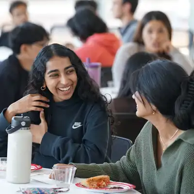 Two students talk at a table.