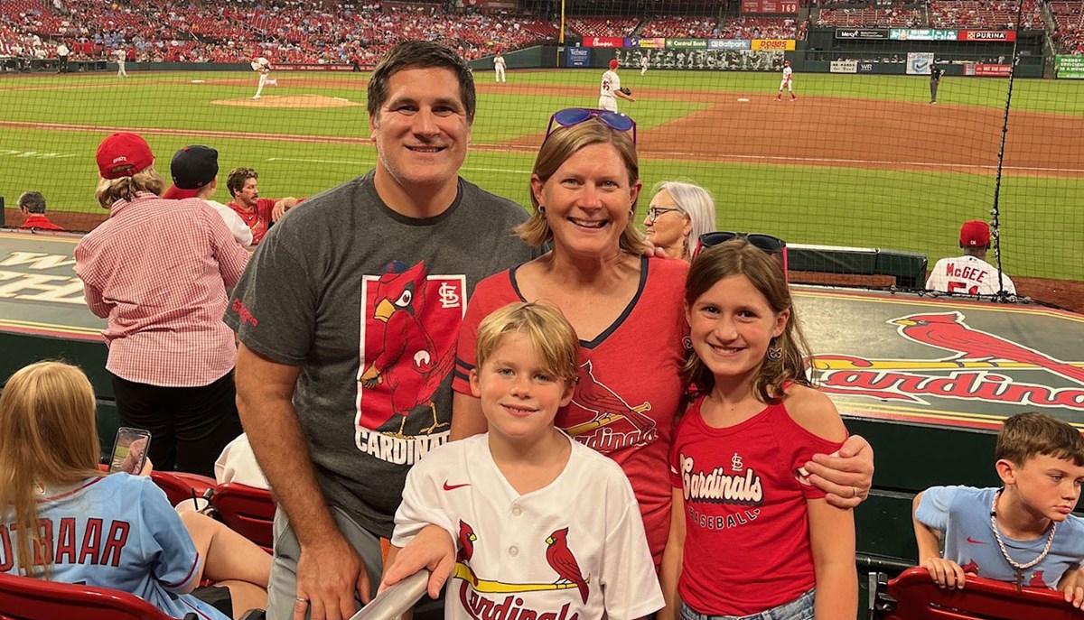 Becky O'Hara and family stand at Cardinals baseball game.