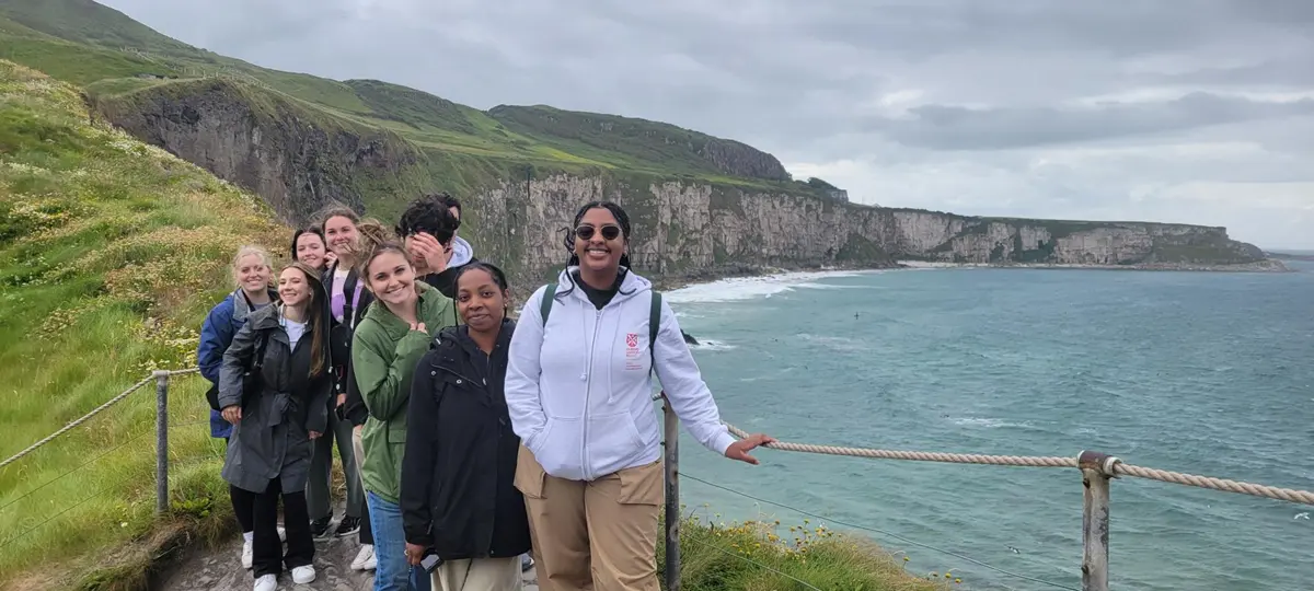 Students standing on a cliff in Ireland with ocean in background.